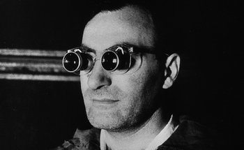 Movie still from “La Jetée” (1962), directed by Chris Marker – A black and white photo of a man wearing glasses; Close Up shot, Low angle