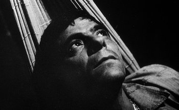 Movie still from “La Jetée” (1962), directed by Chris Marker – An old black and white photo of a man looking up; Close Up shot, Overhead angle