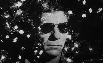 Movie still from “La Jetée” (1962), directed by Chris Marker – A black and white photo of a man wearing sunglasses; Close Up shot, Low angle