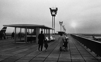 Movie still from “La Jetée” (1962), directed by Chris Marker – A black and white photo of people walking on a sidewalk; Extreme Wide shot, High angle