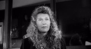 Movie still from “The Bohemian Life” (1992), directed by Aki Kaurismäki – An older woman with long curly hair is looking at the camera; Close Up shot, Low angle