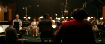 Movie still from “La Vie En Rose” (2007), directed by Olivier Dahan – People are sitting in chairs in a dark room; Medium shot, Over the shoulder angle