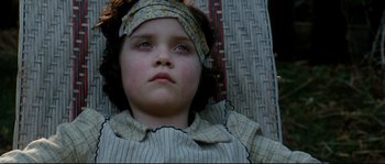 Movie still from “La Vie En Rose” (2007), directed by Olivier Dahan – A young girl with a headband on laying on a bed; Close Up shot, High angle