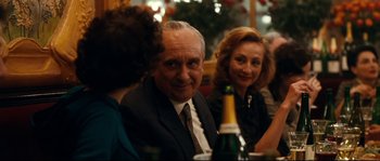 Movie still from “La Vie En Rose” (2007), directed by Olivier Dahan – A group of people sitting at a table with drinks; Close Up shot, Over the shoulder angle