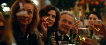 Movie still from “La Vie En Rose” (2007), directed by Olivier Dahan – A group of people sitting at a table with drinks; Close Up shot, Over the shoulder angle