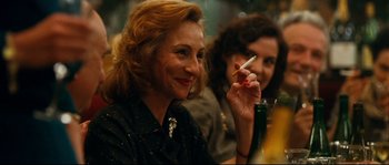 Movie still from “La Vie En Rose” (2007), directed by Olivier Dahan – A woman sitting at a table with a cigarette in her mouth; Close Up shot, Over the shoulder angle