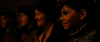 Movie still from “La Vie En Rose” (2007), directed by Olivier Dahan – A boy wearing a hat is looking at the camera; Close Up shot, Over the shoulder angle
