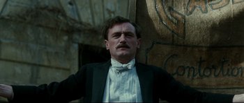 Movie still from “La Vie En Rose” (2007), directed by Olivier Dahan – A man with a mustache wearing a suit and tie; Close Up shot, Low angle