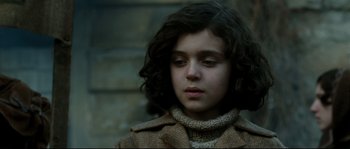 Movie still from “La Vie En Rose” (2007), directed by Olivier Dahan – A young girl in a brown coat looking down at the ground; Close Up shot, Over the shoulder angle