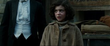 Movie still from “La Vie En Rose” (2007), directed by Olivier Dahan – A young girl wearing a brown coat and a sweater; Close Up shot, Over the shoulder angle