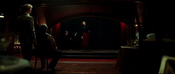 Movie still from “La Vie En Rose” (2007), directed by Olivier Dahan – A woman standing on a stage with a microphone; Wide shot, Over the shoulder angle
