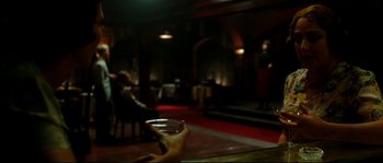 Movie still from “La Vie En Rose” (2007), directed by Olivier Dahan – A person holding a wine glass in front of an audience; Medium shot, Over the shoulder angle