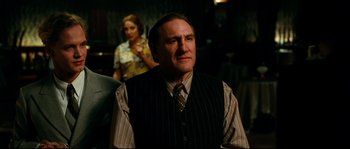 Movie still from “La Vie En Rose” (2007), directed by Olivier Dahan – A man wearing a vest and a striped tie; Medium shot, Over the shoulder angle