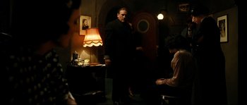 Movie still from “La Vie En Rose” (2007), directed by Olivier Dahan – A man standing in front of a woman in front of a lamp; Medium shot, Over the shoulder angle