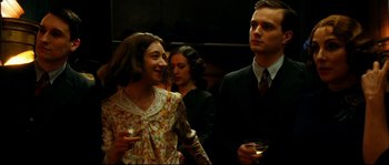 Movie still from “La Vie En Rose” (2007), directed by Olivier Dahan – A man and a woman standing next to each other holding wine glasses; Medium shot, Over the shoulder angle