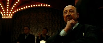 Movie still from “La Vie En Rose” (2007), directed by Olivier Dahan – An older man in a suit and tie looking at the camera; Close Up shot, Low angle