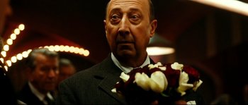 Movie still from “La Vie En Rose” (2007), directed by Olivier Dahan – An older man holding a bouquet of roses; Close Up shot, Over the shoulder angle