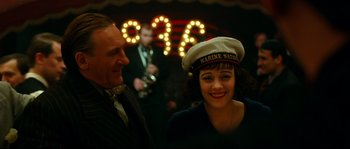 Movie still from “La Vie En Rose” (2007), directed by Olivier Dahan – A man and a woman are standing in front of lights; Medium shot, Over the shoulder angle