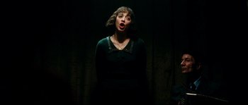 Movie still from “La Vie En Rose” (2007), directed by Olivier Dahan – A woman in a dark room singing a song; Medium shot, Low angle