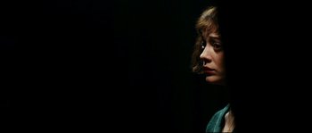 Movie still from “La Vie En Rose” (2007), directed by Olivier Dahan – A woman is looking to her left in the dark; Close Up shot, Over the shoulder angle