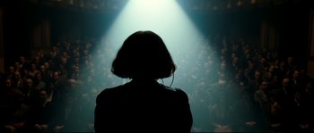 Movie still from “La Vie En Rose” (2007), directed by Olivier Dahan – A person with headphones in front of an audience; Medium shot, Low angle