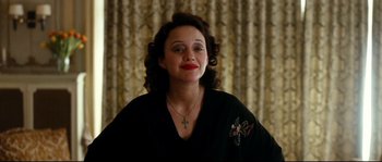 Movie still from “La Vie En Rose” (2007), directed by Olivier Dahan – A woman with a cross on her chest and red lipstick on her lips; Close Up shot, High angle