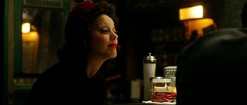 Movie still from “La Vie En Rose” (2007), directed by Olivier Dahan – A woman sitting at a table in front of some food; Close Up shot, Low angle