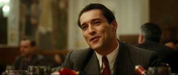 Movie still from “La Vie En Rose” (2007), directed by Olivier Dahan – A person wearing a suit and tie; Close Up shot, Over the shoulder angle