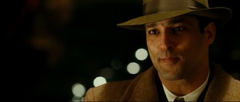 Movie still from “La Vie En Rose” (2007), directed by Olivier Dahan – A person wearing a suit and a hat; Close Up shot, Over the shoulder angle