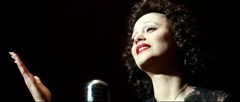 Movie still from “La Vie En Rose” (2007), directed by Olivier Dahan – A person with a microphone; Close Up shot, High angle