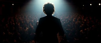Movie still from “La Vie En Rose” (2007), directed by Olivier Dahan – A person standing in front of an audience at a concert; Medium shot, Low angle