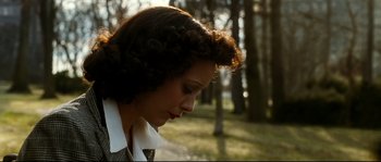 Movie still from “La Vie En Rose” (2007), directed by Olivier Dahan – A young woman with curly brown hair is looking down; Close Up shot, Low angle