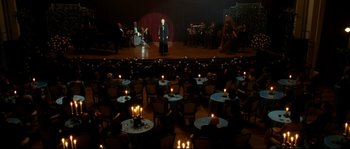 Movie still from “La Vie En Rose” (2007), directed by Olivier Dahan – A man standing on a stage in front of an orchestra; Extreme Wide shot, High angle