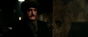 Movie still from “La Vie En Rose” (2007), directed by Olivier Dahan – A man with a mustache wearing a hat and a scarf; Close Up shot, Over the shoulder angle