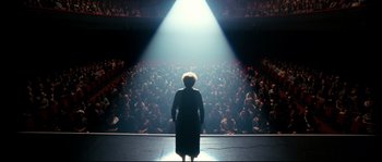 Movie still from “La Vie En Rose” (2007), directed by Olivier Dahan – A woman standing in front of an audience on a stage; Extreme Wide shot, Low angle
