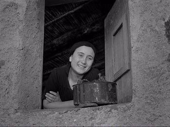 Movie still from “The Earth Trembles” (1948), directed by Luchino Visconti – A woman leaning out of a window next to an old suitcase; Medium shot, Low angle