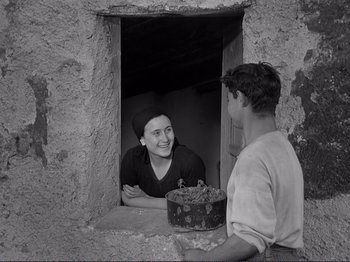 Movie still from “The Earth Trembles” (1948), directed by Luchino Visconti – A man and a woman are standing in an open window; Medium shot, Over the shoulder angle