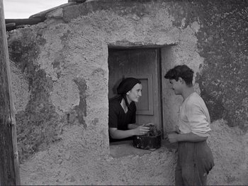 Movie still from “The Earth Trembles” (1948), directed by Luchino Visconti – An old photo of a man and a woman looking out of a window; Medium shot, Low angle