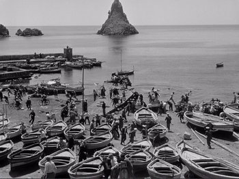 Movie still from “The Earth Trembles” (1948), directed by Luchino Visconti – A black and white photo of a beach with many boats; Extreme Wide shot, High angle