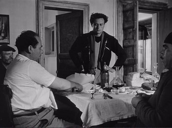 Movie still from “The Earth Trembles” (1948), directed by Luchino Visconti – Two men sitting at a table with a wine glass; Medium shot, Over the shoulder angle