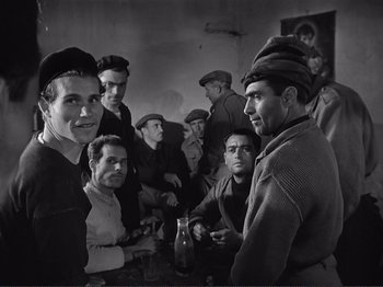 Movie still from “The Earth Trembles” (1948), directed by Luchino Visconti – A black and white photo of a group of men sitting at a table; Medium shot, Low angle