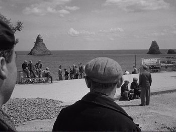 Movie still from “The Earth Trembles” (1948), directed by Luchino Visconti – A group of people standing on top of a sandy beach; Extreme Wide shot, High angle