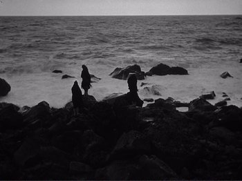 Movie still from “The Earth Trembles” (1948), directed by Luchino Visconti – A group of people standing on top of a rocky beach; Extreme Wide shot, High angle