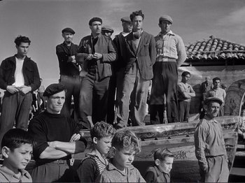 Movie still from “The Earth Trembles” (1948), directed by Luchino Visconti – A black and white photo of a group of men standing next to each other; Wide shot, Low angle