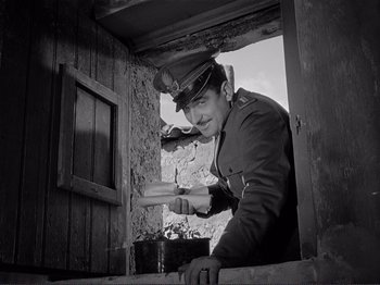 Movie still from “The Earth Trembles” (1948), directed by Luchino Visconti – An old photo of a man in a uniform pointing to a window; Medium shot, Low angle