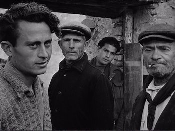 Movie still from “The Earth Trembles” (1948), directed by Luchino Visconti – A black and white photo of a group of men; Medium shot, Low angle