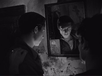 Movie still from “The Earth Trembles” (1948), directed by Luchino Visconti – A man looking at himself in the mirror; Close Up shot, Over the shoulder angle