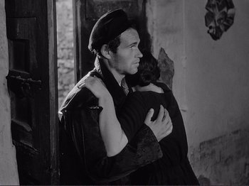 Movie still from “The Earth Trembles” (1948), directed by Luchino Visconti – A man and a woman hugging in a room; Medium shot, Over the shoulder angle