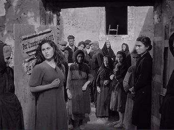 Movie still from “The Earth Trembles” (1948), directed by Luchino Visconti – A group of people standing in front of a building; Wide shot, High angle