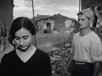 Movie still from “The Earth Trembles” (1948), directed by Luchino Visconti – A man and a woman standing in front of an old building; Medium shot, Low angle